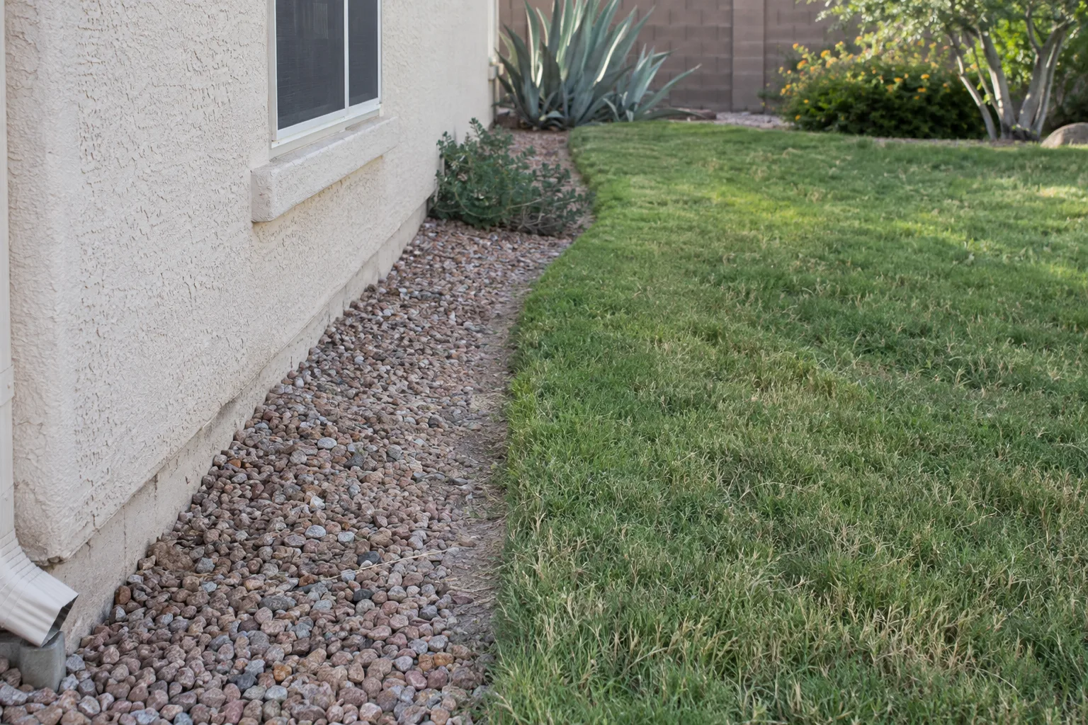 Gravel strip separating a stucco foundation from the lawn to keep mites away