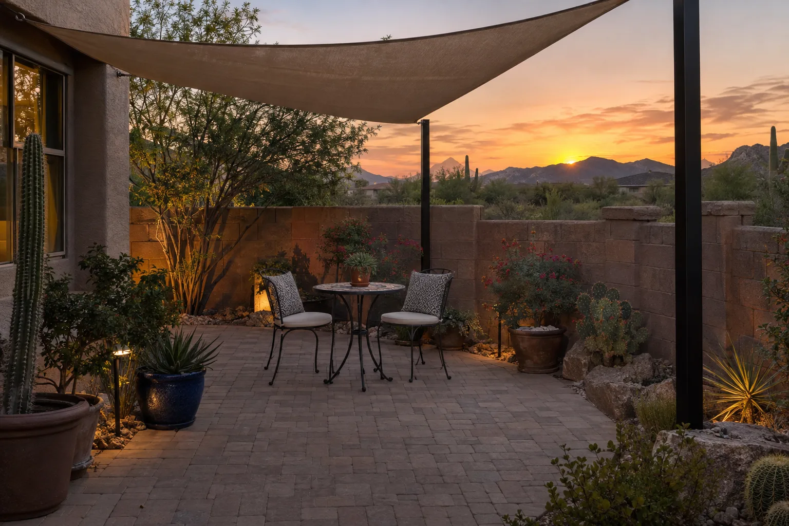 Shaded small patio with a table, chairs and potted plants beside a block wall
